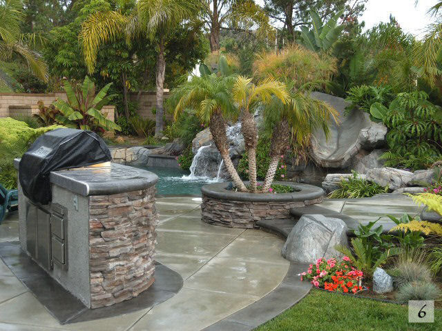 Esempio di una grande piscina naturale stile americano personalizzata dietro casa con fontane e lastre di cemento