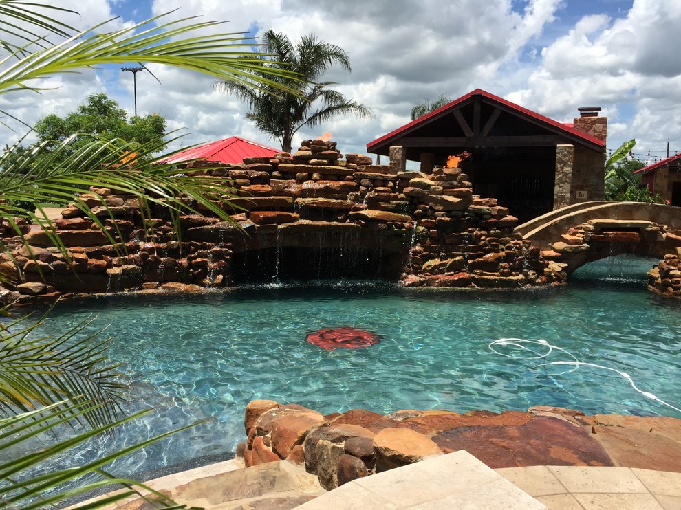 Imagen de piscina con fuente rural grande a medida en patio trasero con adoquines de piedra natural