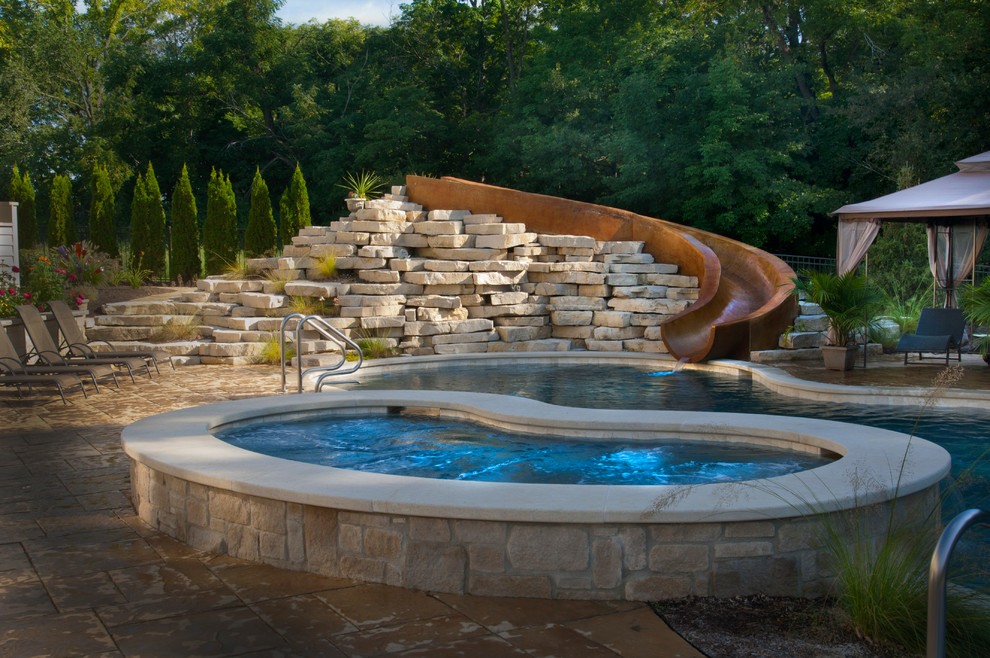 На фото: естественный бассейн среднего размера, произвольной формы на заднем дворе в классическом стиле с джакузи и мощением тротуарной плиткой с