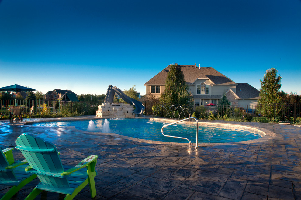 This is an example of a medium sized classic back custom shaped swimming pool in Chicago with a water slide and concrete paving.