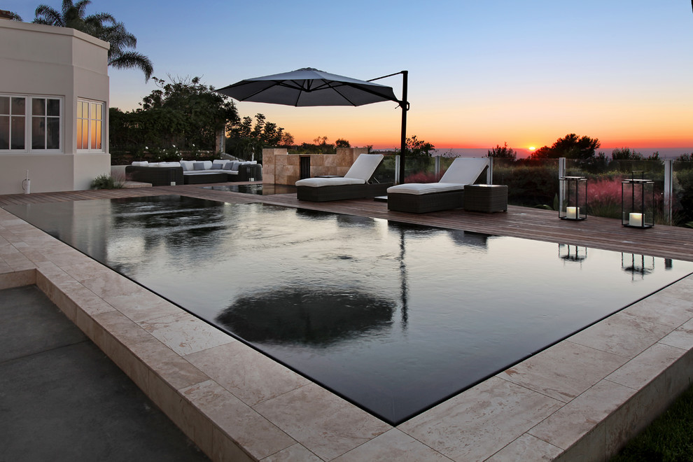 This is an example of a medium sized contemporary back custom shaped infinity swimming pool in Orange County with decking.