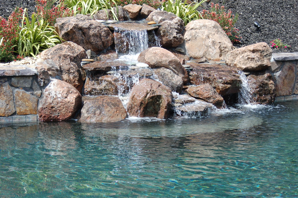 Exemple d'une grande piscine arrière exotique sur mesure avec un point d'eau et du béton estampé.