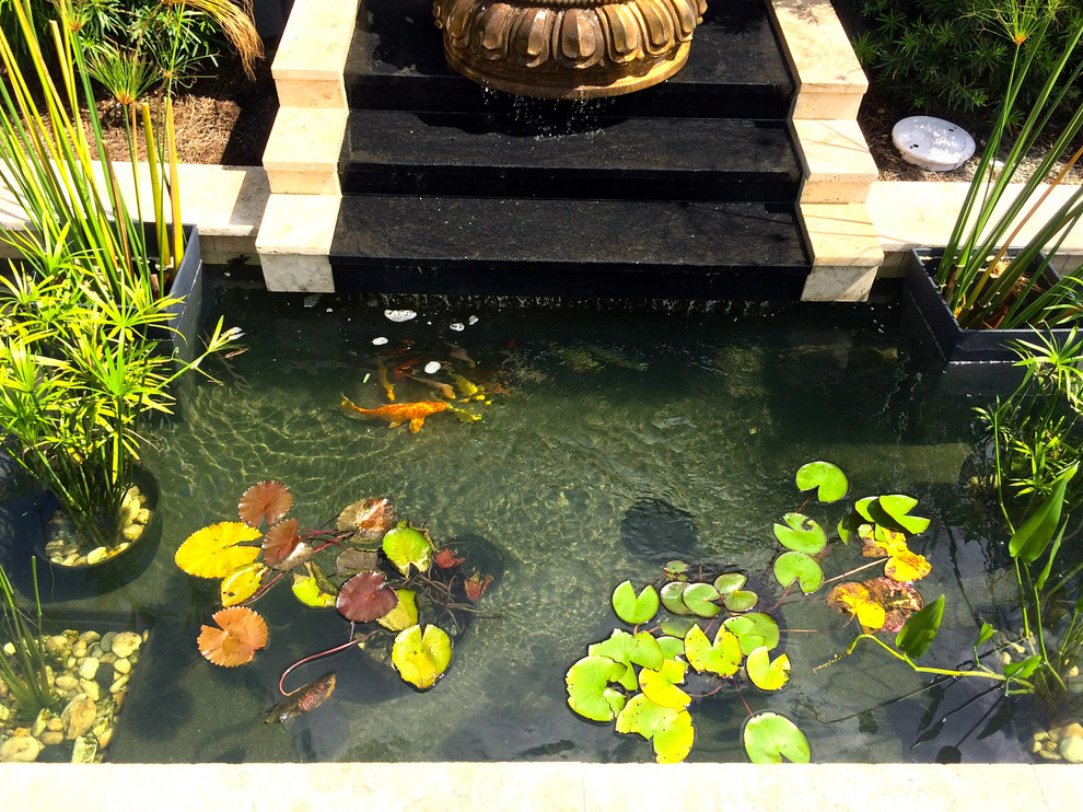 Idée de décoration pour une petite piscine naturelle et arrière sur mesure avec un point d'eau et des pavés en pierre naturelle.