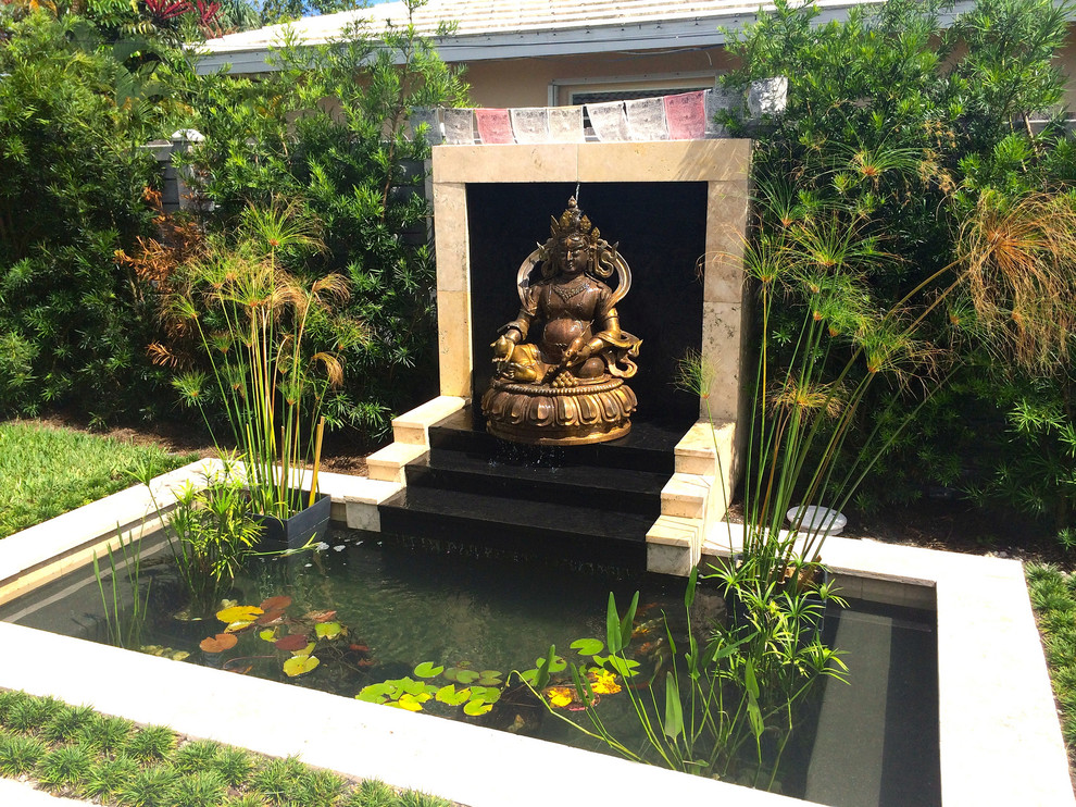 Foto på en liten orientalisk baddamm på baksidan av huset, med en fontän och naturstensplattor