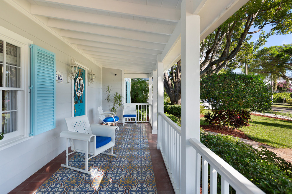 This is an example of a huge traditional tile front porch design in Miami with a roof extension.