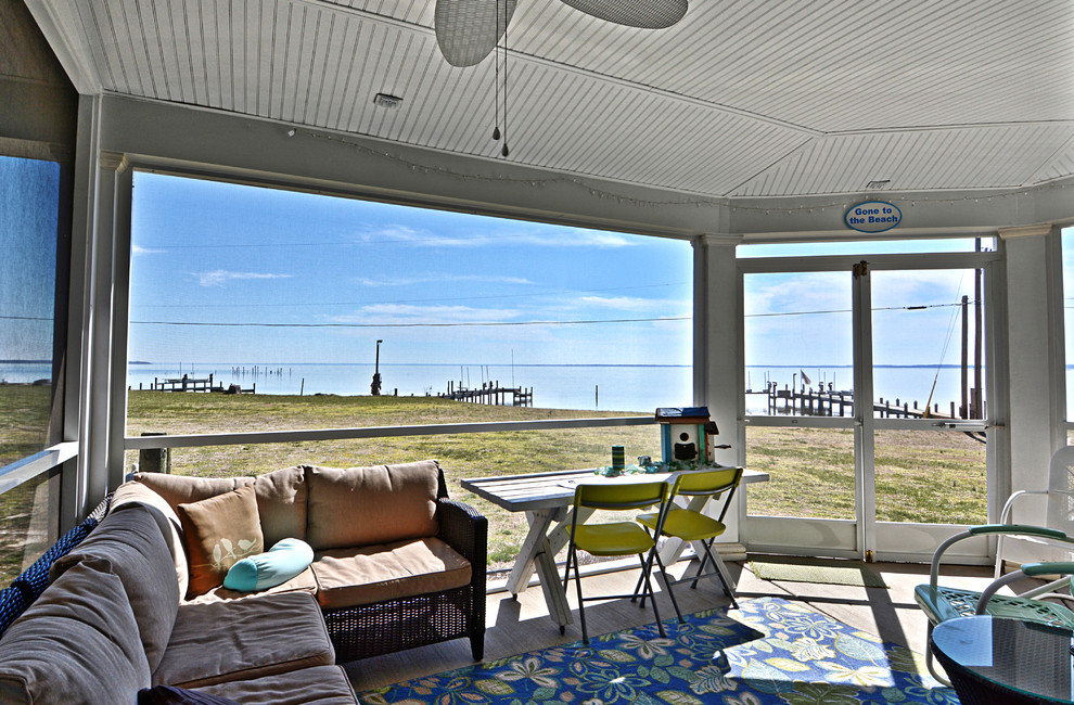 Photo of a medium sized beach style back screened veranda in DC Metro with a roof extension.