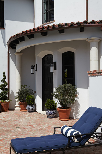 Modelo de terraza mediterránea en patio delantero con adoquines de ladrillo y jardín de macetas