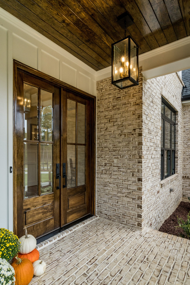 Cette image montre un porche d'entrée de maison avant rustique avec des pavés en brique.