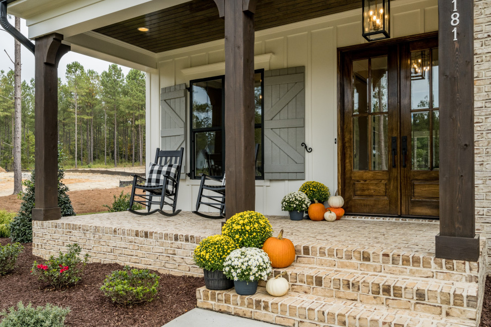 Immagine di un portico country davanti casa con pavimentazioni in mattoni