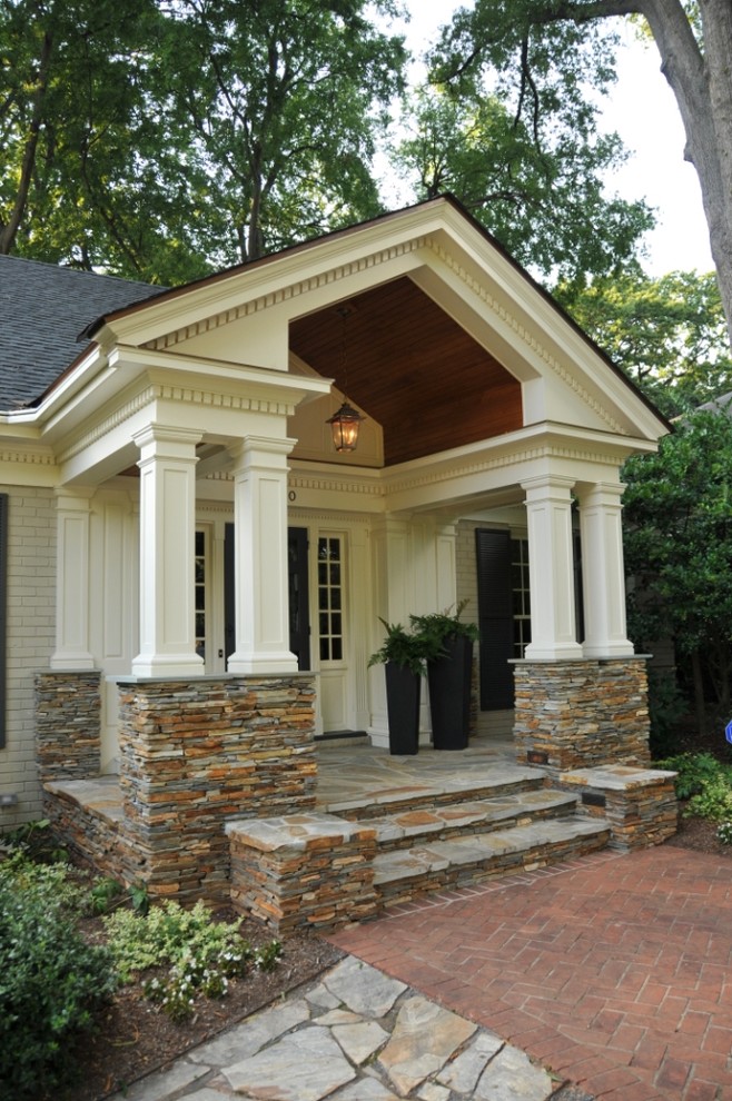 Foto di un portico classico davanti casa con pavimentazioni in pietra naturale e un tetto a sbalzo