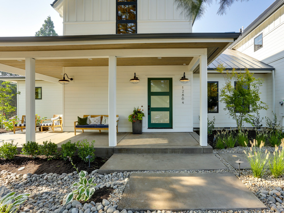 Diseño de terraza de estilo de casa de campo extra grande en patio delantero y anexo de casas con adoquines de hormigón