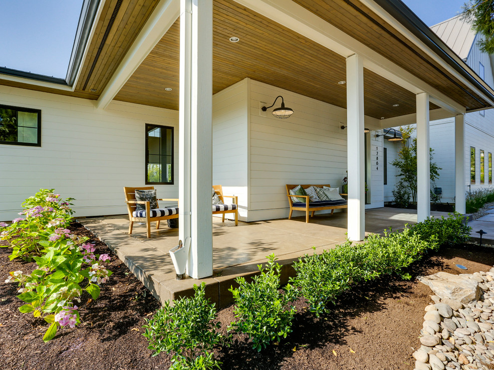 Exemple d'un très grand porche d'entrée de maison avant nature avec une extension de toiture.