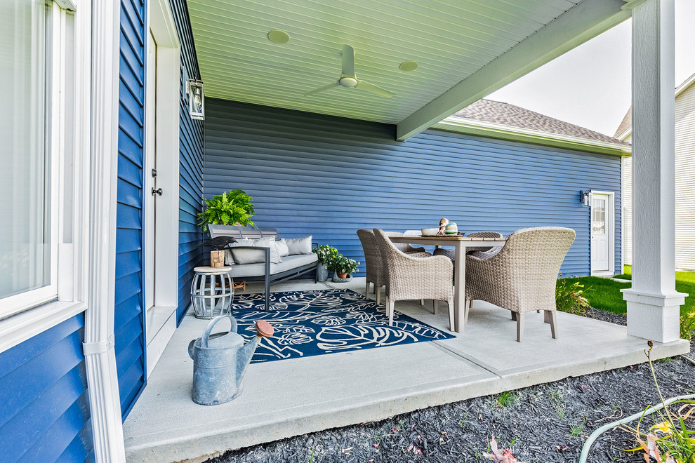 На фото: веранда среднего размера на заднем дворе в стиле кантри с покрытием из бетонных плит и навесом