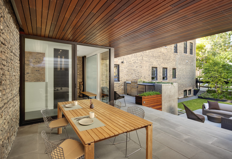 Aménagement d'un grand porche d'entrée de maison arrière contemporain avec une cuisine d'été, une extension de toiture et des pavés en béton.