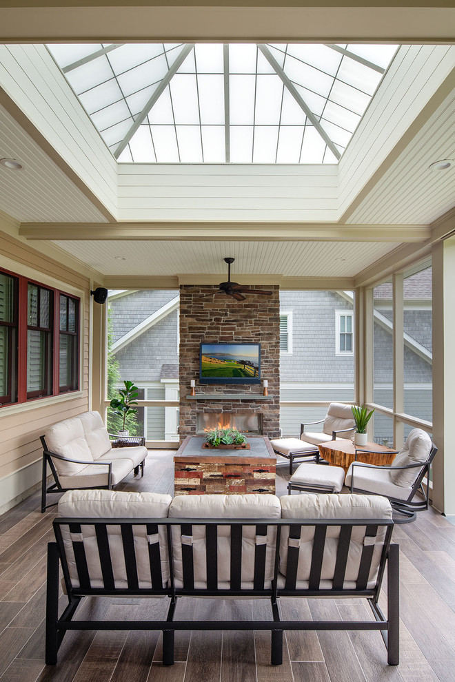 Large transitional stone back porch idea in DC Metro with a fireplace and a roof extension