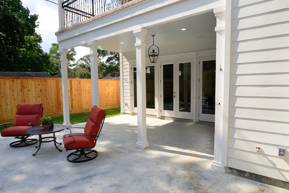 This is an example of a large traditional concrete paver back porch design in Houston with a roof extension.