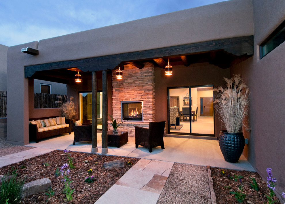 Idée de décoration pour un porche d'entrée de maison arrière sud-ouest américain de taille moyenne avec un foyer extérieur, une dalle de béton et une extension de toiture.