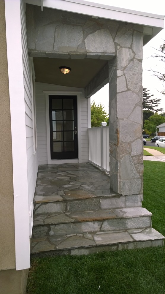 Inspiration for a small coastal stone front porch remodel in Los Angeles with a roof extension