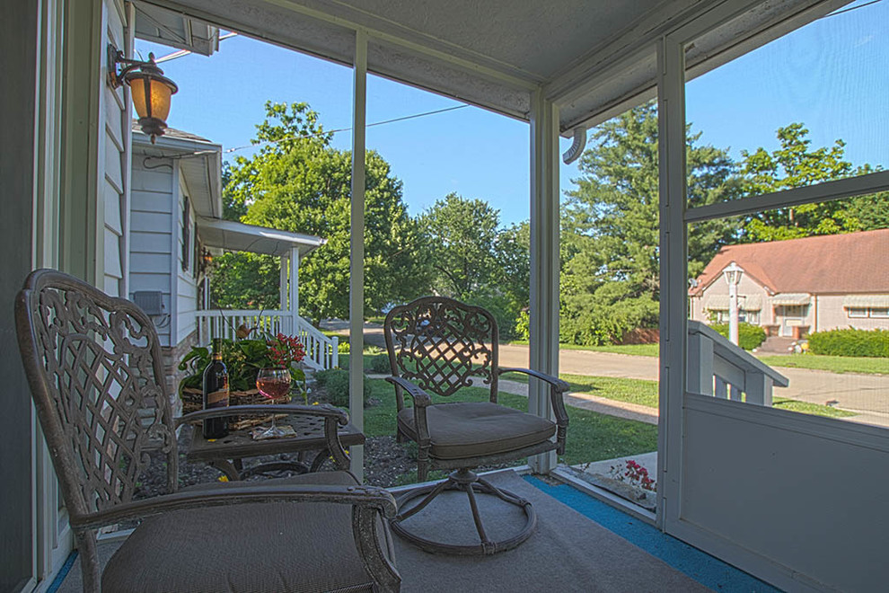Cette image montre un porche d'entrée de maison avant bohème avec une moustiquaire, une dalle de béton et une extension de toiture.