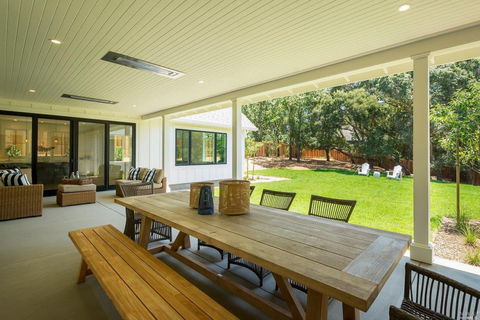 Inspiration pour un grand porche d'entrée de maison arrière rustique avec du béton estampé et une extension de toiture.