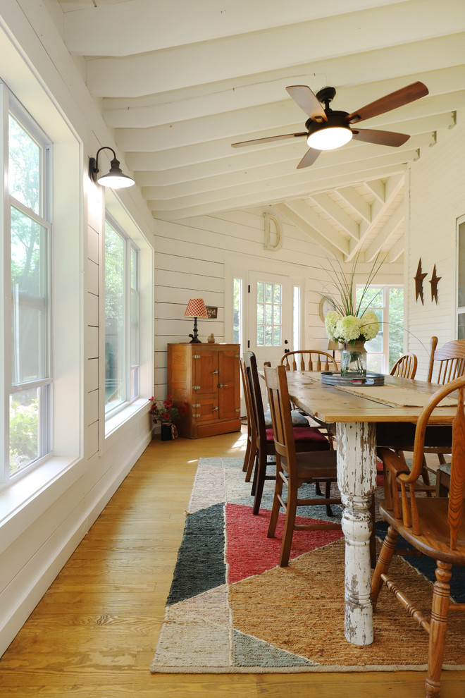 Photo of an expansive farmhouse front veranda in Grand Rapids with a roof extension and feature lighting.