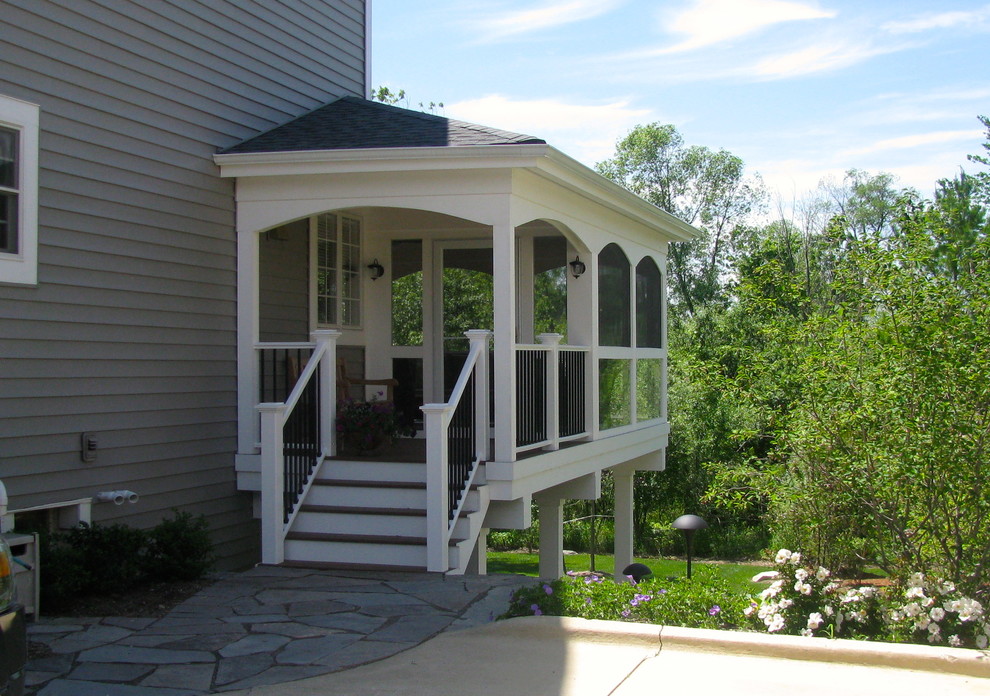 This is an example of a large modern stone screened-in back porch design in Detroit with a roof extension.