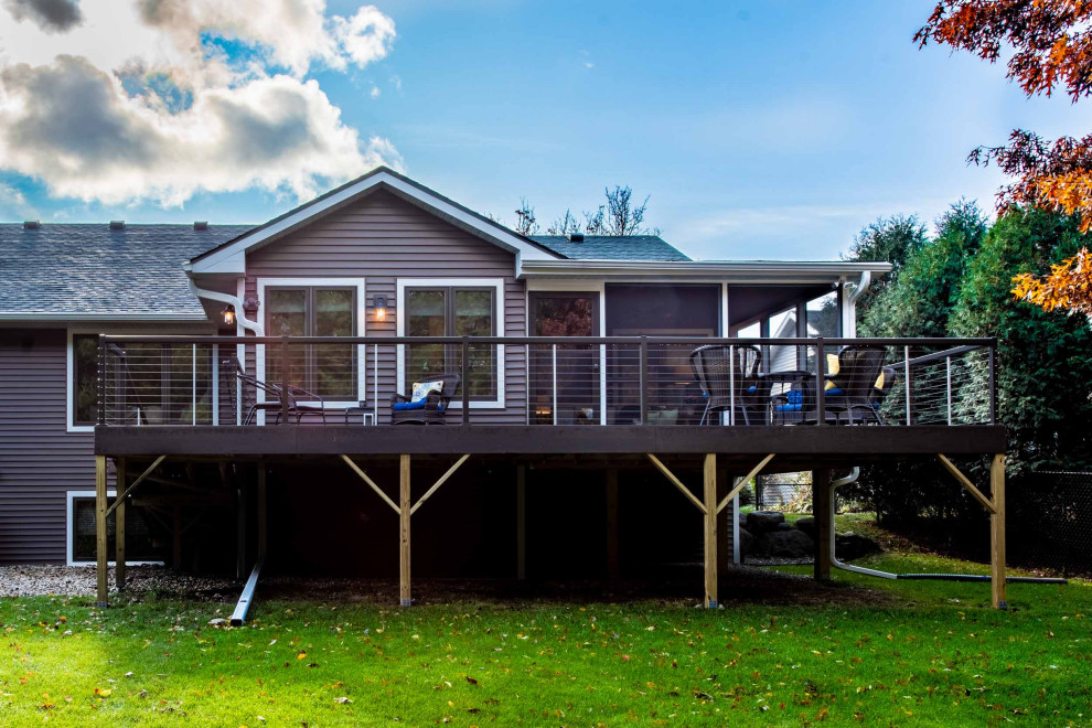 Exempel på en mellanstor lantlig innätad veranda på baksidan av huset, med trädäck och takförlängning