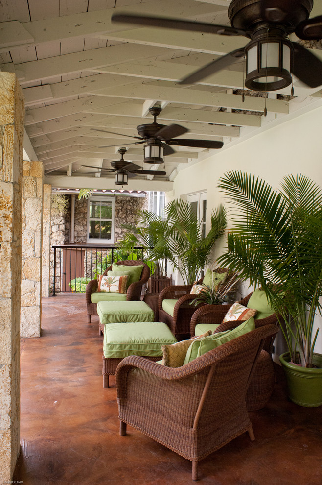 Huge island style concrete back porch photo in Miami with a roof extension