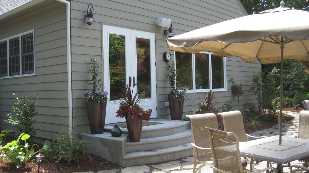 Klassisk inredning av en liten veranda på baksidan av huset, med utekrukor och betongplatta