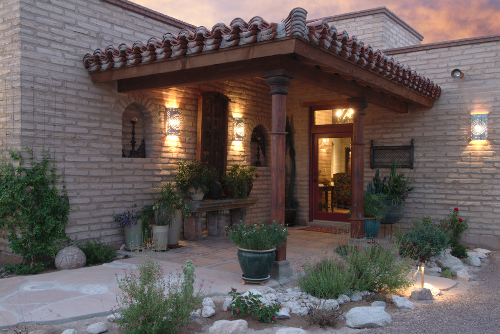 Idée de décoration pour un porche d'entrée de maison avant sud-ouest américain de taille moyenne avec une extension de toiture et du carrelage.