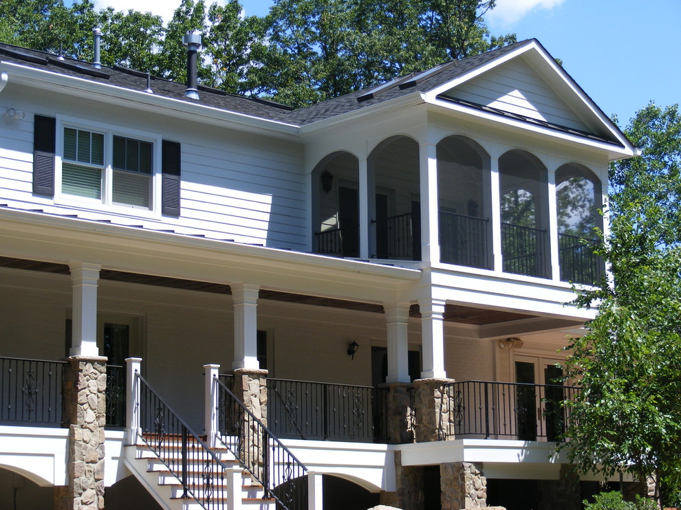 This is an example of a large traditional screened-in front porch design in DC Metro with decking and a roof extension.