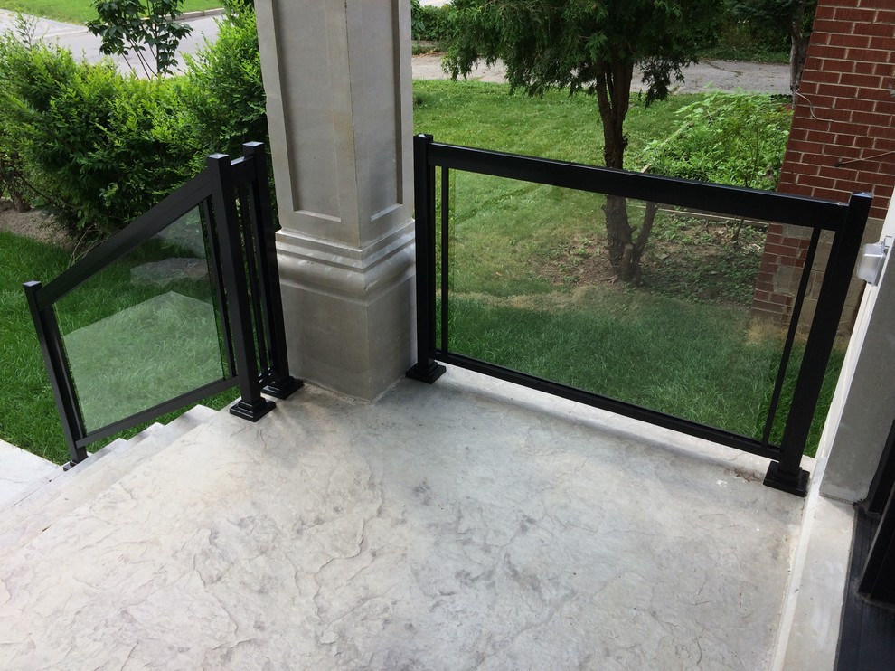 This is an example of a small contemporary front veranda in Toronto with stamped concrete.