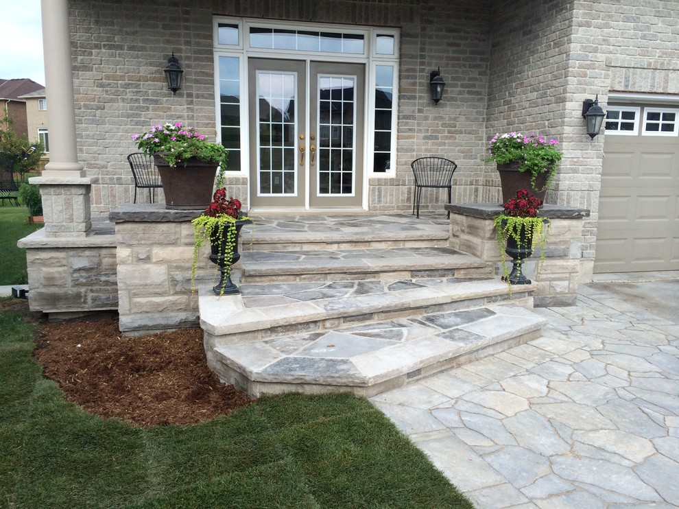 Photo of a medium sized traditional front veranda in Toronto with natural stone paving and a roof extension.