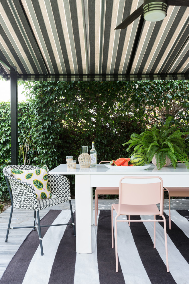 Diseño de terraza costera de tamaño medio en patio trasero con jardín vertical, entablado y toldo