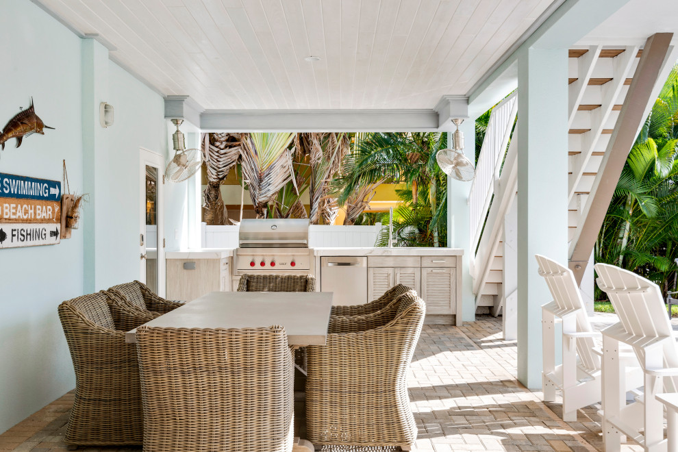 На фото: веранда на заднем дворе в морском стиле с летней кухней, мощением клинкерной брусчаткой и навесом