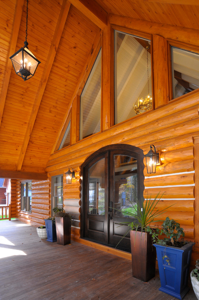 Réalisation d'un grand porche d'entrée de maison arrière chalet avec une terrasse en bois et une extension de toiture.