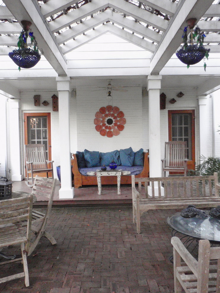 This is an example of a traditional brick side porch design in Houston with a pergola.