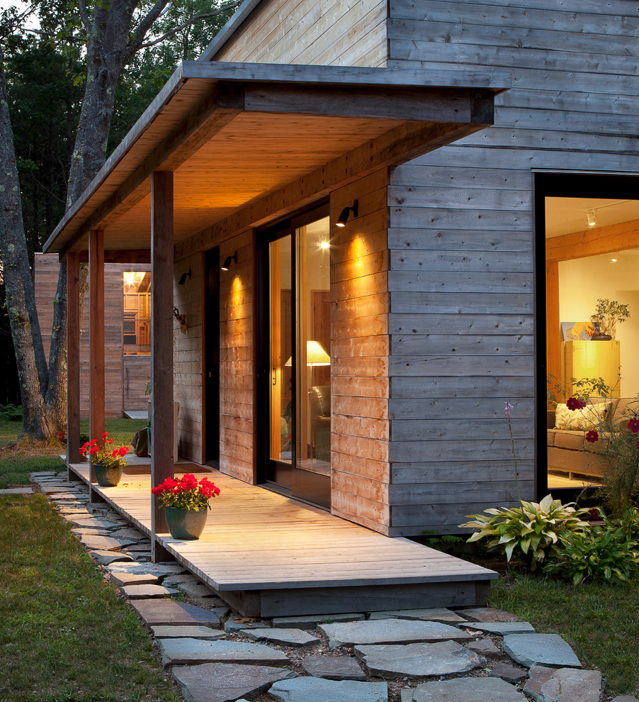 Cette photo montre un porche d'entrée de maison tendance avec une terrasse en bois et une extension de toiture.