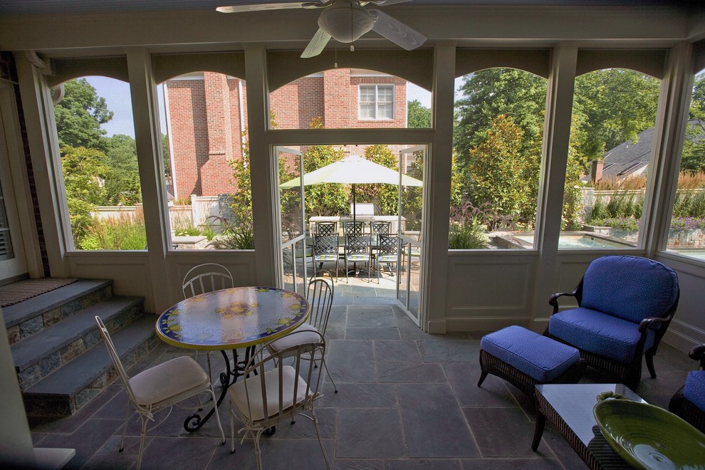 Mid-sized classic stone screened-in back porch idea in DC Metro with a roof extension