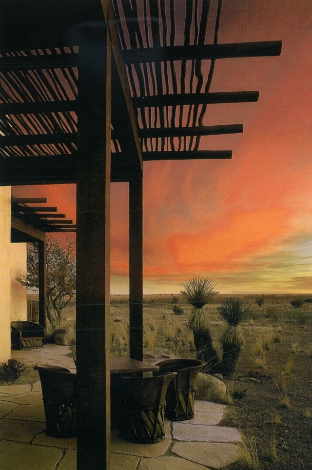 This is an example of a southwestern stone side porch design in Other with a pergola.