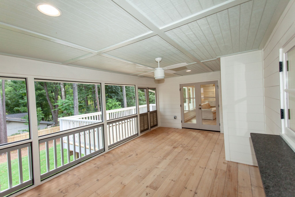This is an example of a large traditional screened-in back porch design in Atlanta with a roof extension.