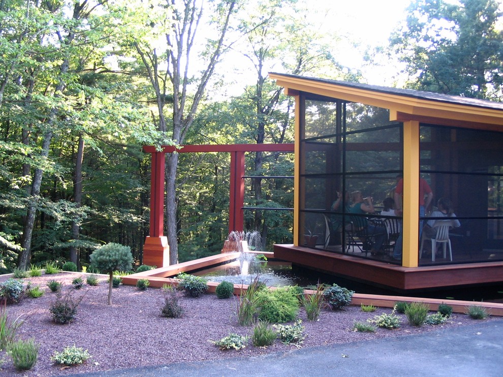 This is an example of a small mid-century modern screened-in front porch design in Boston with a pergola.