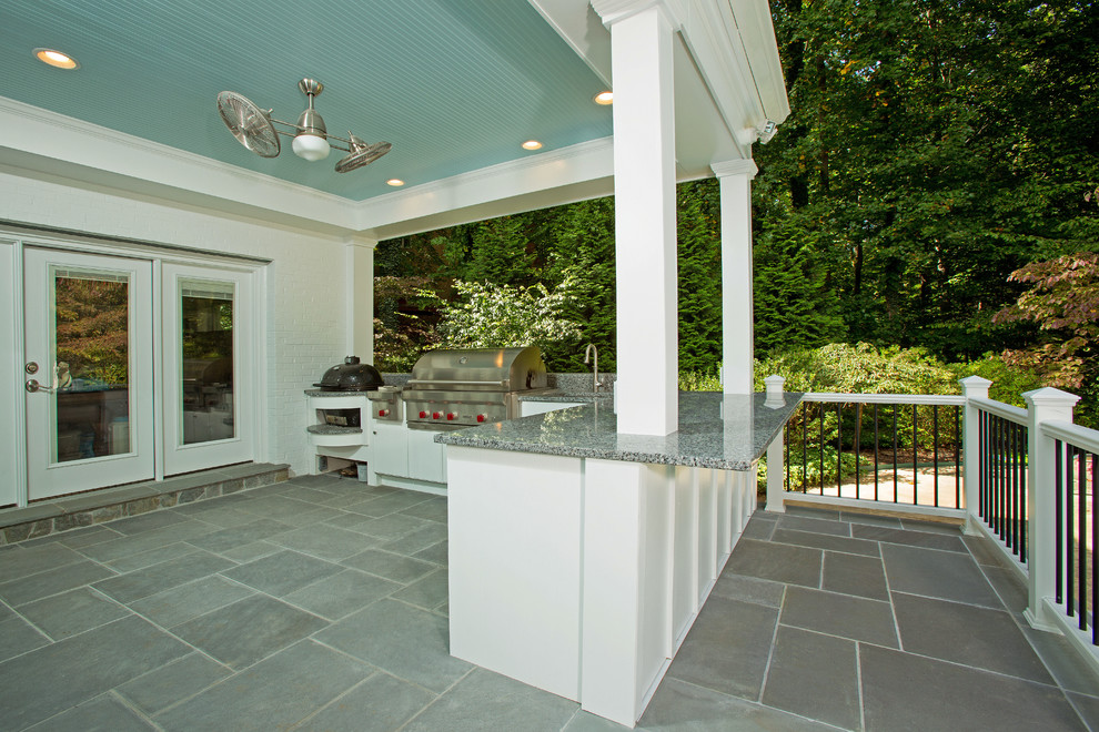 Ejemplo de terraza grande en patio trasero y anexo de casas con cocina exterior y adoquines de piedra natural