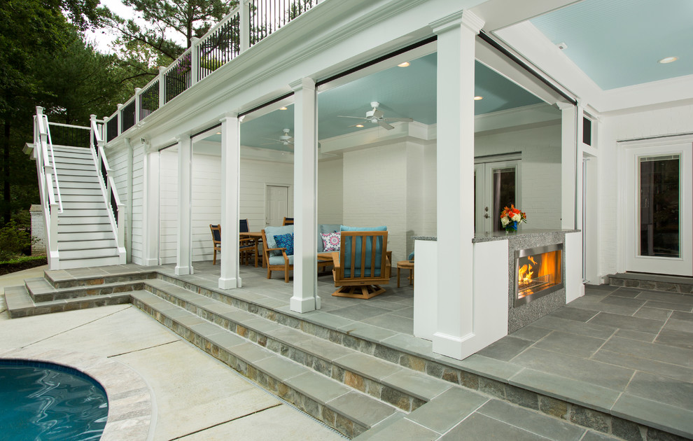 This is an example of a large back screened veranda in DC Metro with natural stone paving and a roof extension.