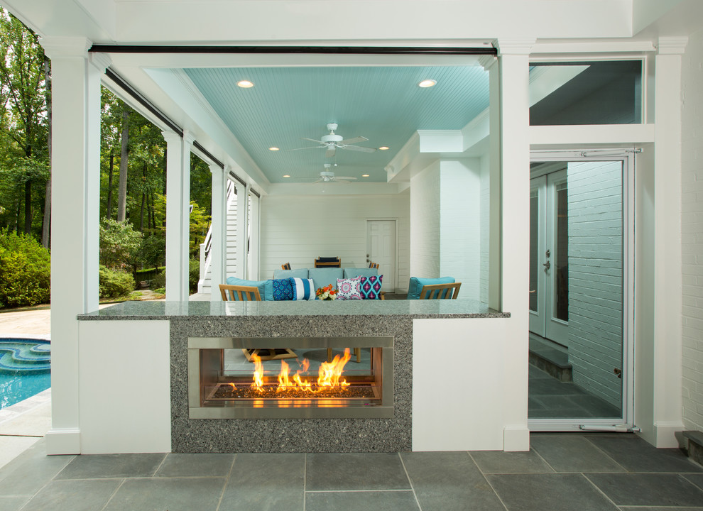 Inspiration for a large back screened veranda in DC Metro with natural stone paving and a roof extension.