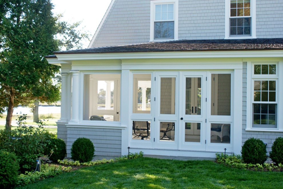 Cette photo montre un porche d'entrée de maison latéral chic de taille moyenne avec une moustiquaire, une terrasse en bois et une extension de toiture.