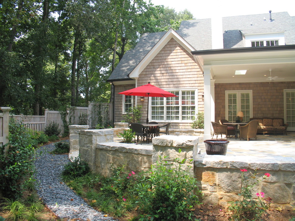 Idee per un patio o portico chic di medie dimensioni e dietro casa con pavimentazioni in pietra naturale e un tetto a sbalzo