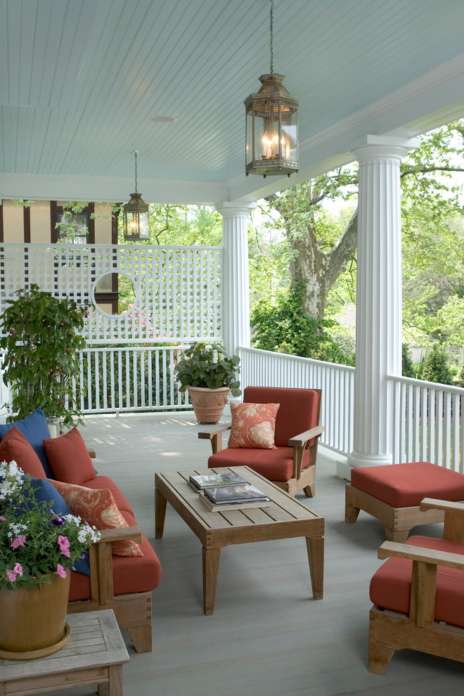 Cette photo montre un grand porche d'entrée de maison arrière chic avec une terrasse en bois et une extension de toiture.