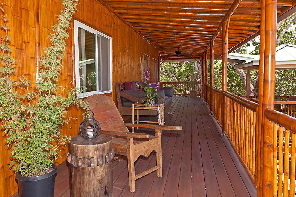 Réalisation d'un porche d'entrée de maison ethnique avec une terrasse en bois et une extension de toiture.
