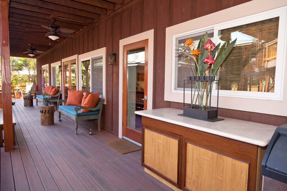Aménagement d'un porche d'entrée de maison exotique avec une terrasse en bois et une extension de toiture.